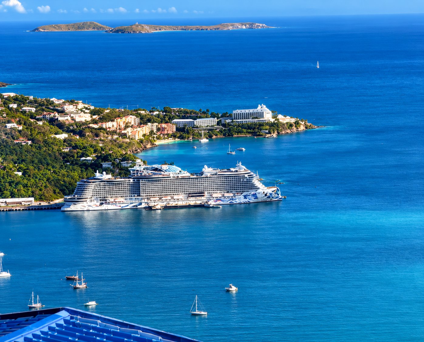 Cruise ship docked in a blue Caribbean bay with sailboats and hillside homes in St. Thomas