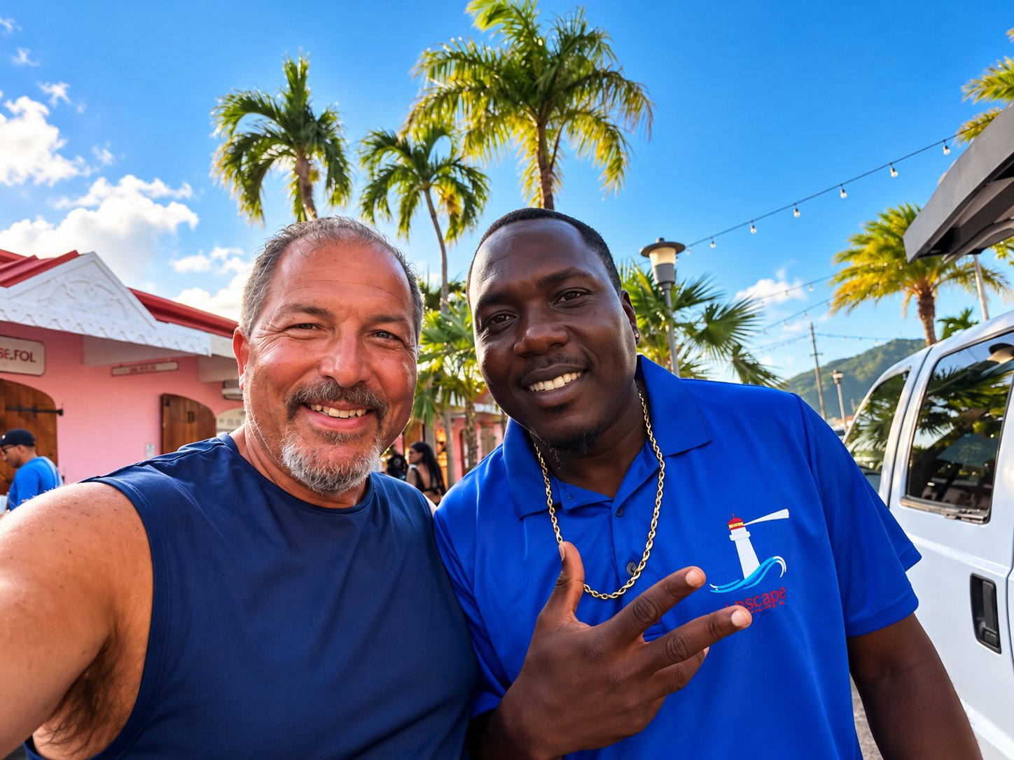 V&K Island Escape team member in a blue company shirt taking a selfie with a guest under palm trees
